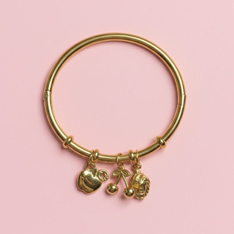 Gold bracelet with charms on a pink background